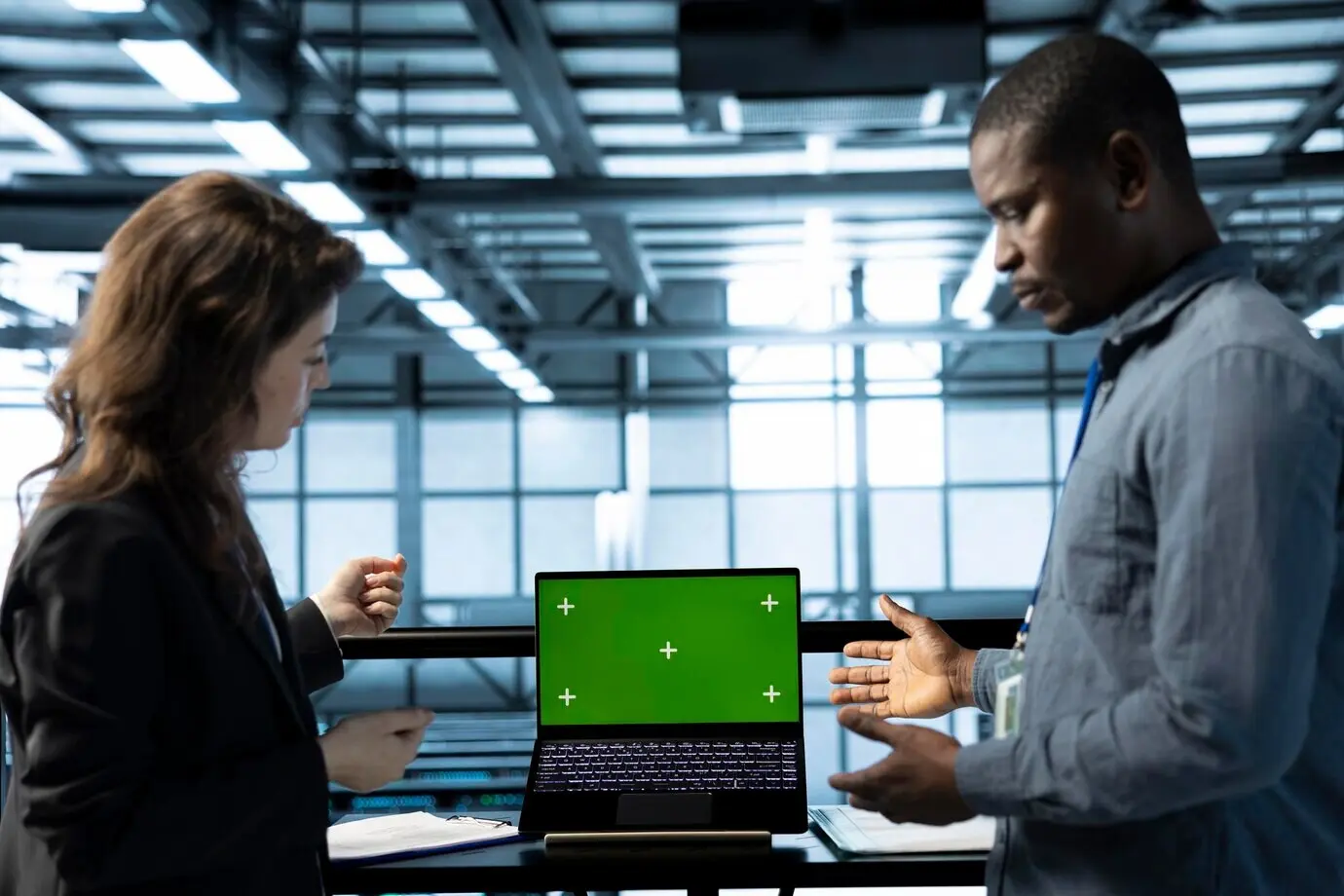 Engineers in a data center using a laptop with an isolated screen mockup.